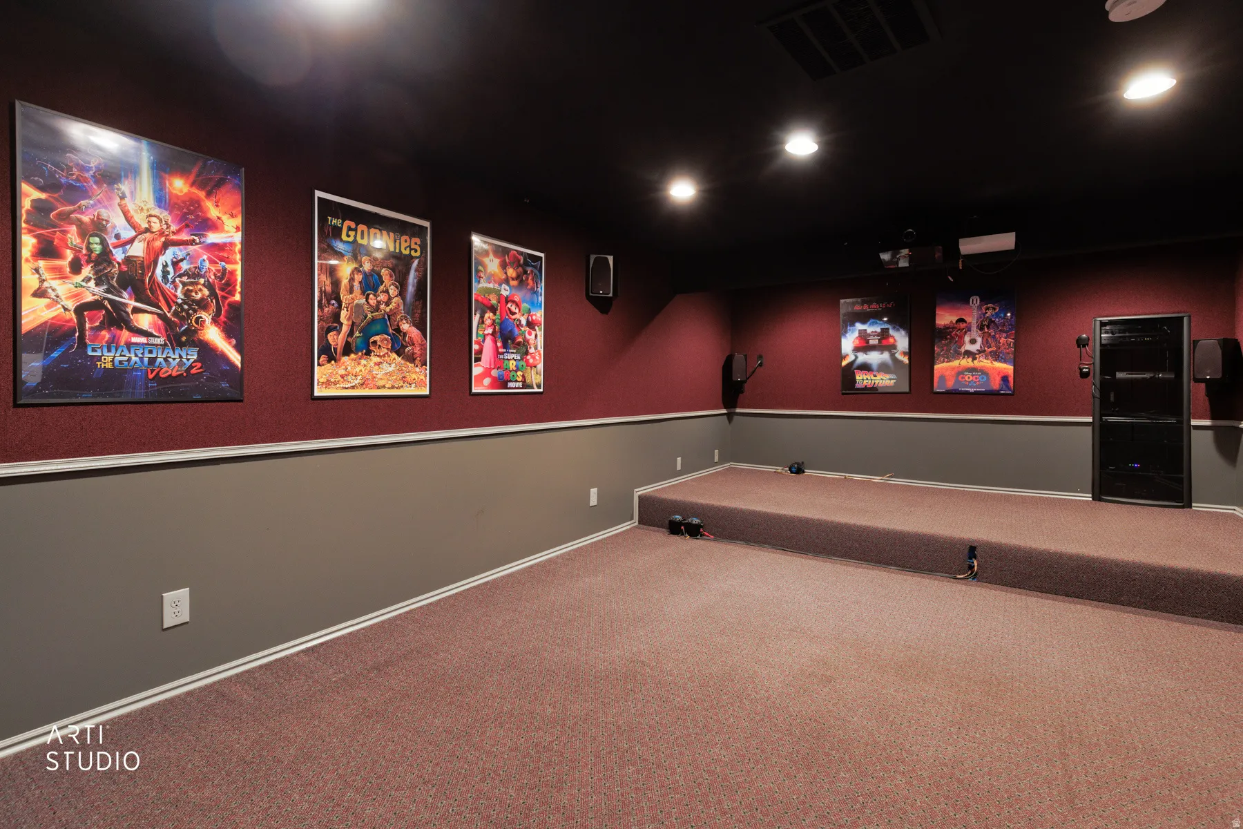 Theatre room with tiered carpeting, built-in projector, recessed lighting, wall-mounted speakers, and a two-tone wall treatment