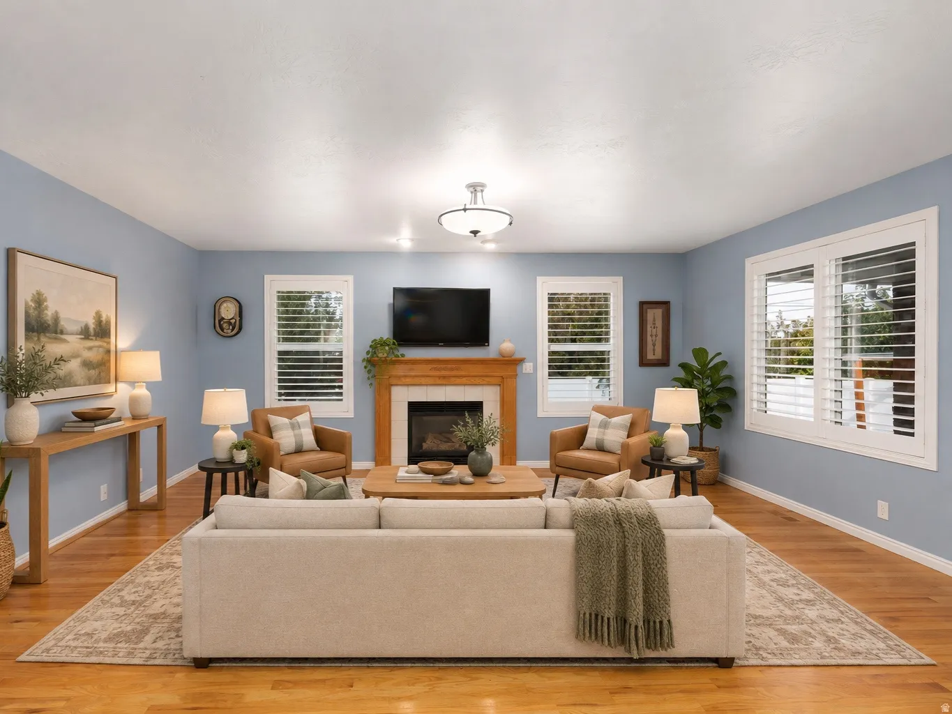 Hardwood-finish flooring, built-in fireplace with wood mantel, multiple windows with plantation shutters, and a ceiling-mounted light fixture