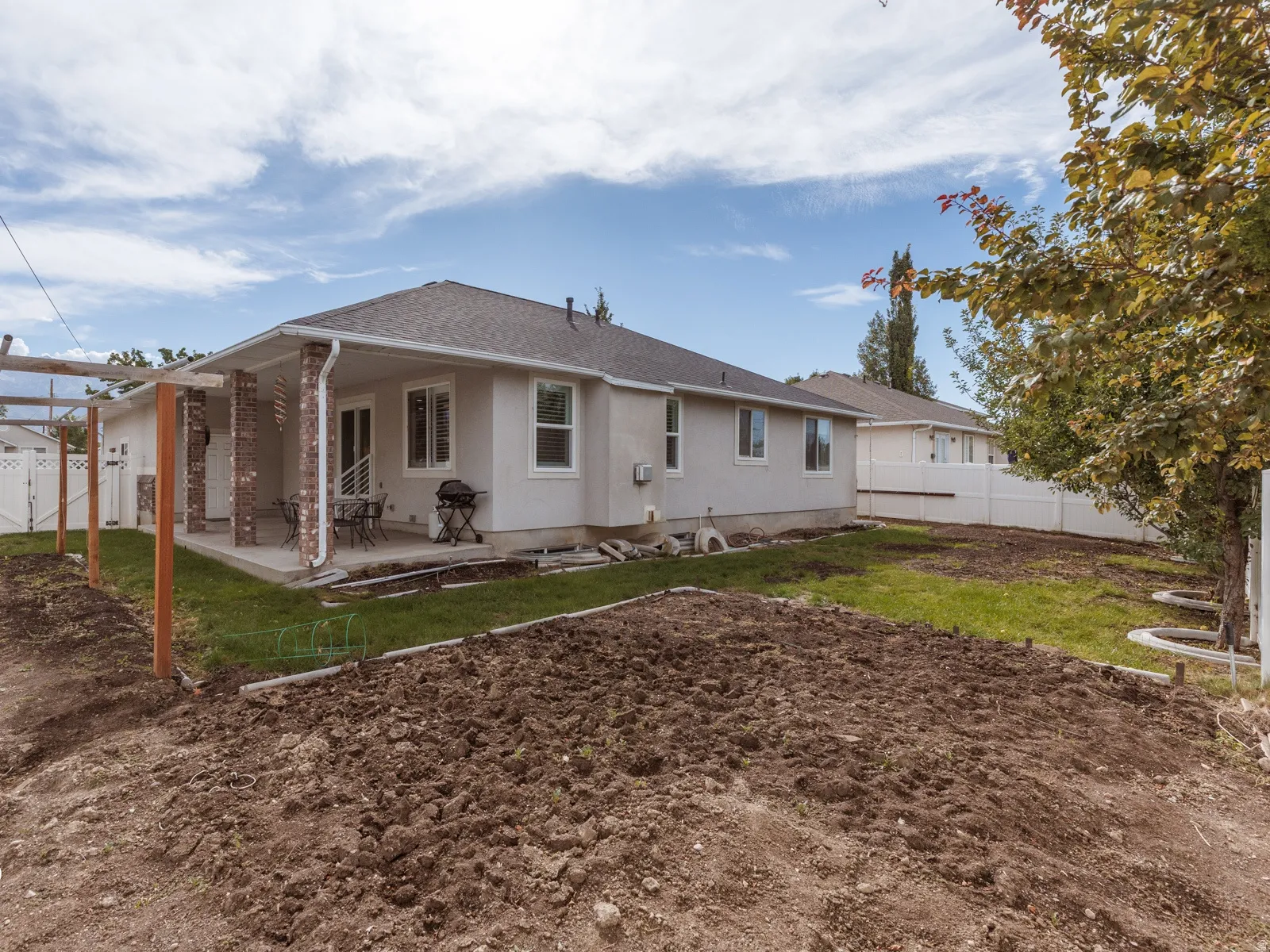 Rear concrete patio with brick pillars and stucco exterior