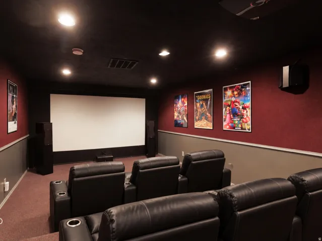 Dedicated home theater featuring a large projection screen, recessed ceiling lights, and wall-mounted speakers with digitally staged furniture.