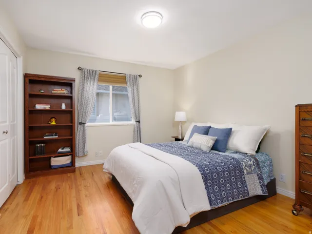 Hardwood flooring, neutral wall tones, window with vertical blinds, ceiling-mounted light fixture, and white bi-fold closet doors