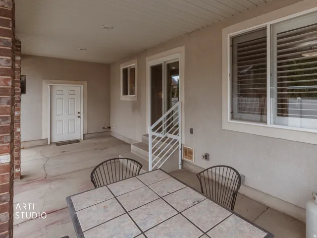 Covered patio with a stucco exterior, brick column, and a sliding glass door