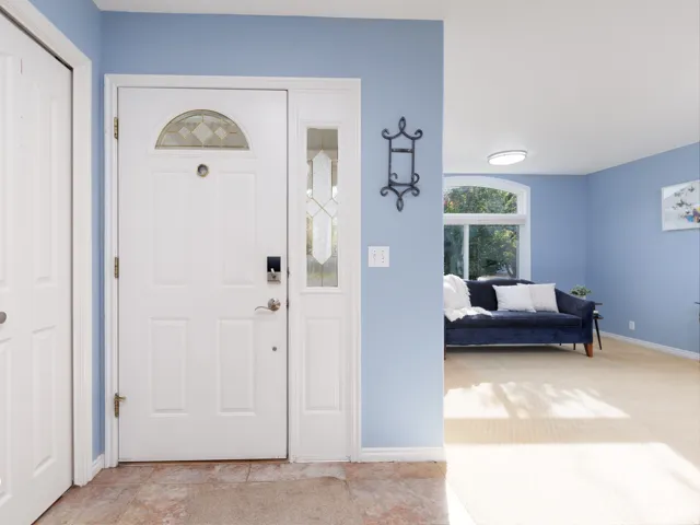 Entryway featuring a white paneled door with decorative glass, a sidelight, and a transom window