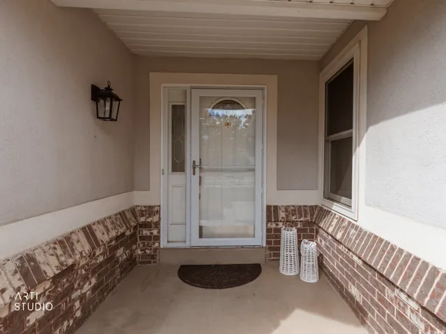 Covered entry with stucco and brick facade