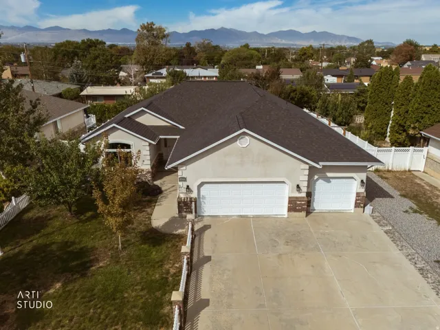 Stucco exterior with brick accents, attached multi-car garage, concrete driveway, and mature landscaping