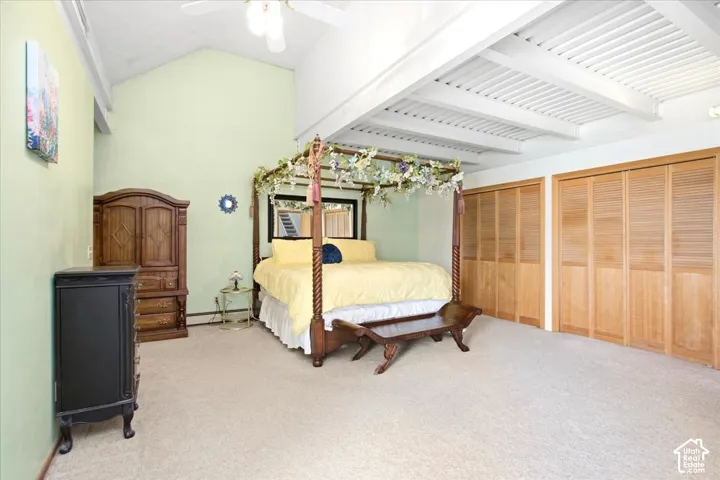 Vaulted ceiling with exposed beams, ceiling fan, and light-toned carpeting