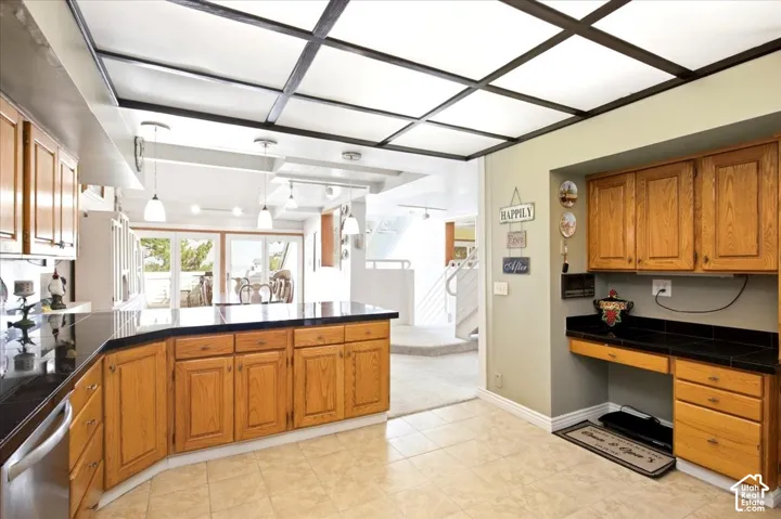 Kitchen featuring wood cabinetry, black countertops, tile flooring, and a coffered ceiling