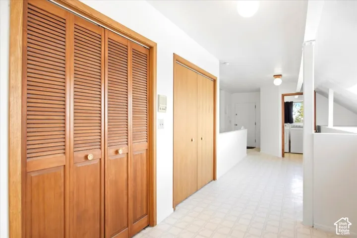 Hallway featuring light-toned flooring, white walls, and wood-finish doors
