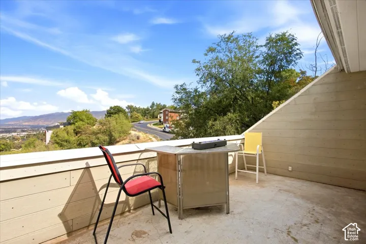 Private balcony with concrete flooring, sloped wall, and distant mountain scenery