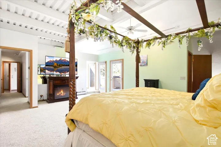 White vaulted ceiling with exposed beams, carpeted flooring, built-in electric fireplace with mantel, ceiling fan, and double doors