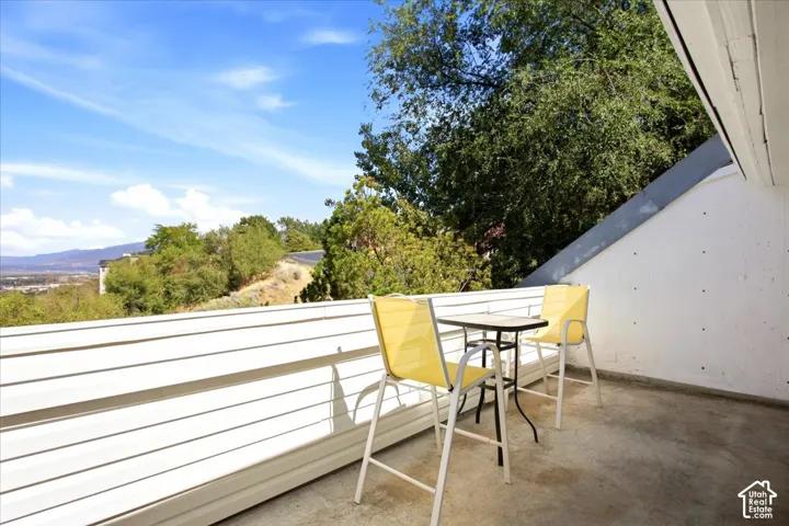 Concrete patio with white siding, mountain scenery, and mature trees