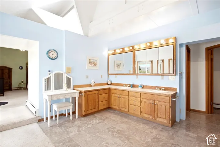 Dual vanity with light wood cabinetry and integrated sinks, large format floor tiling, and exposed beam ceiling