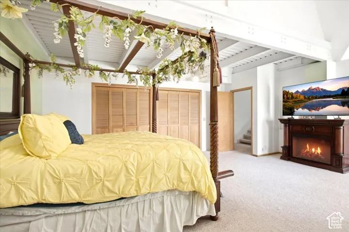 Recessed lighting, wood-finish bi-fold closet doors, exposed ceiling beams, and a built-in electric fireplace