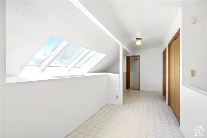 Angled skylights, patterned flooring, wood-finish doors, flush mount ceiling fixture, half-wall partition