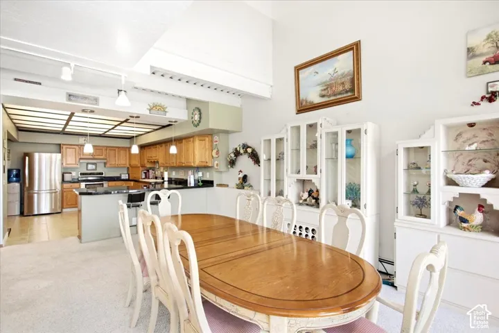 Kitchen featuring stainless steel refrigerator, wood-finish cabinetry, black countertops, and pendant lighting