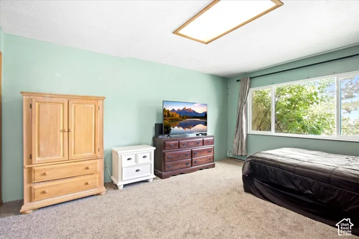 Recessed ceiling light fixture, light-toned carpeting, and a large window providing natural illumination