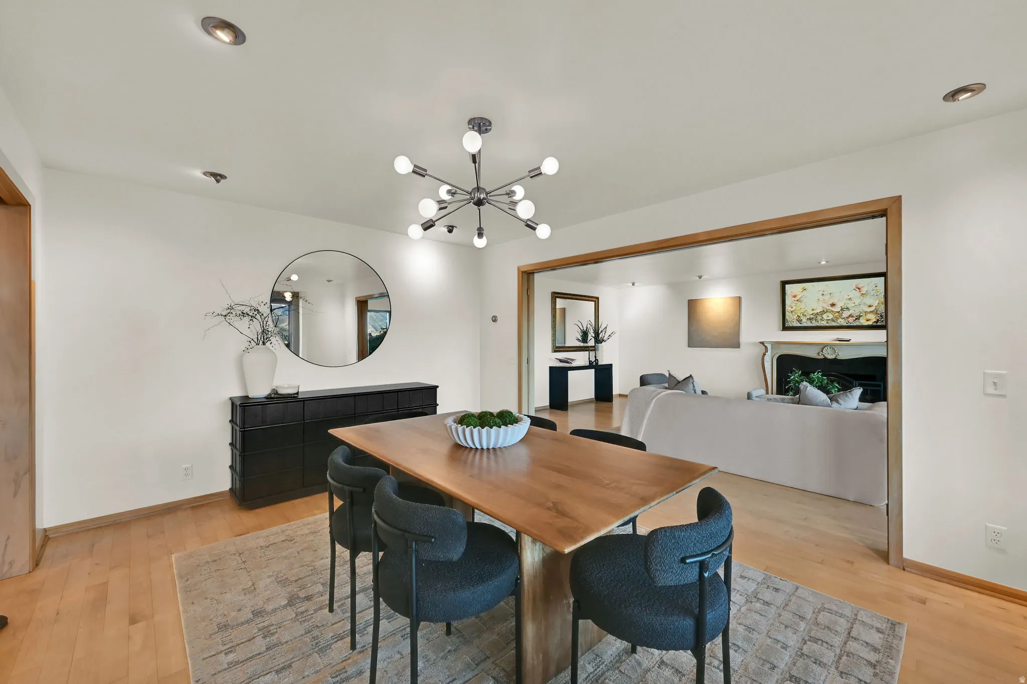 Recessed ceiling lighting, wood-finish flooring, and a wide cased opening into an additional room