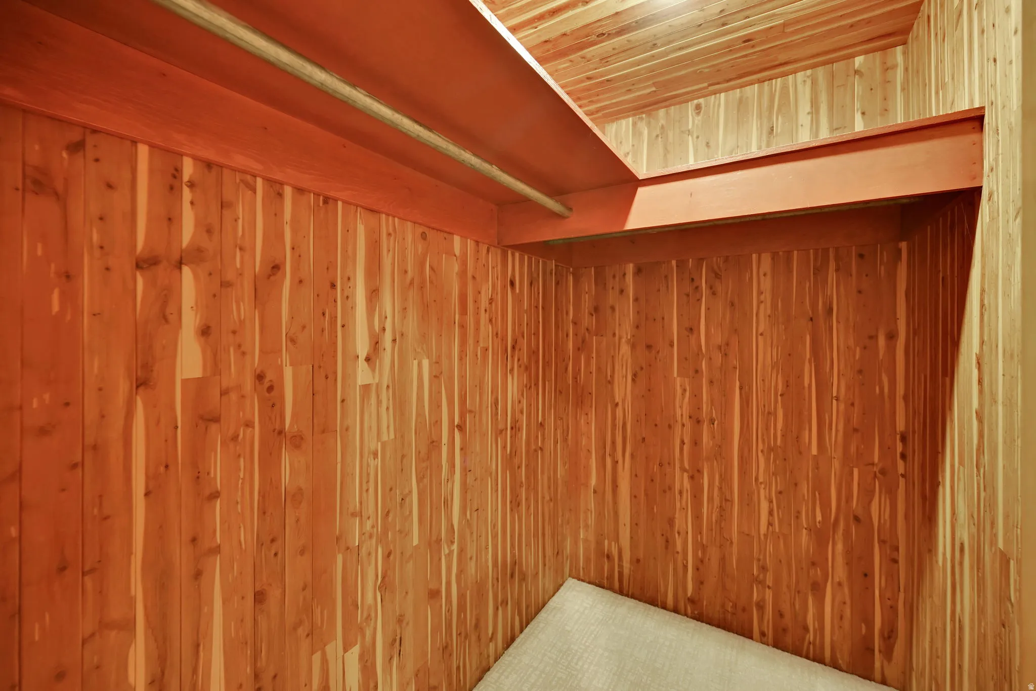 Wood-paneled cedar walls and ceiling with a built-in shelf and hanging rod