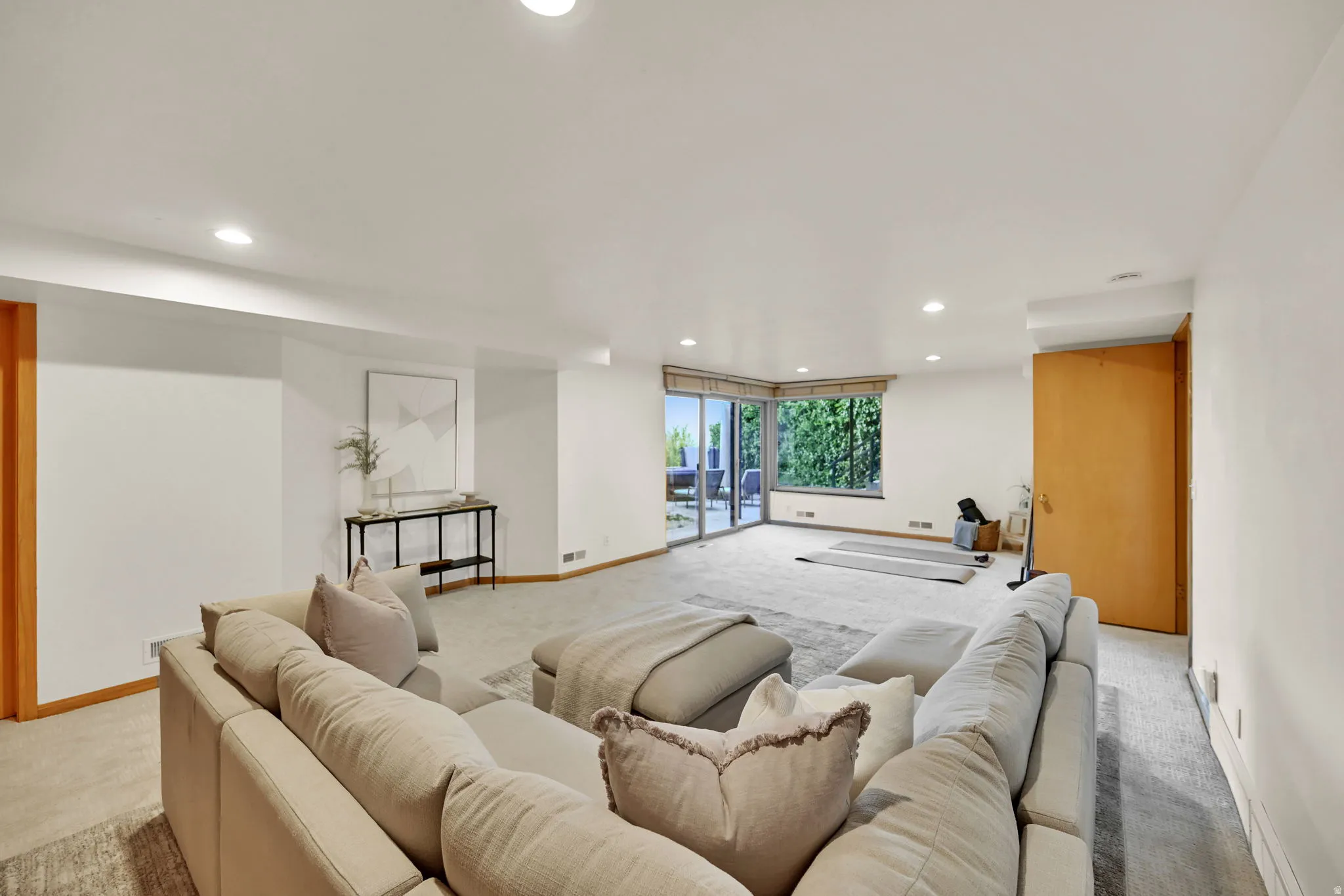 Recessed lighting, wood-finish door, light-colored carpeting, large windows, and glass sliding doors