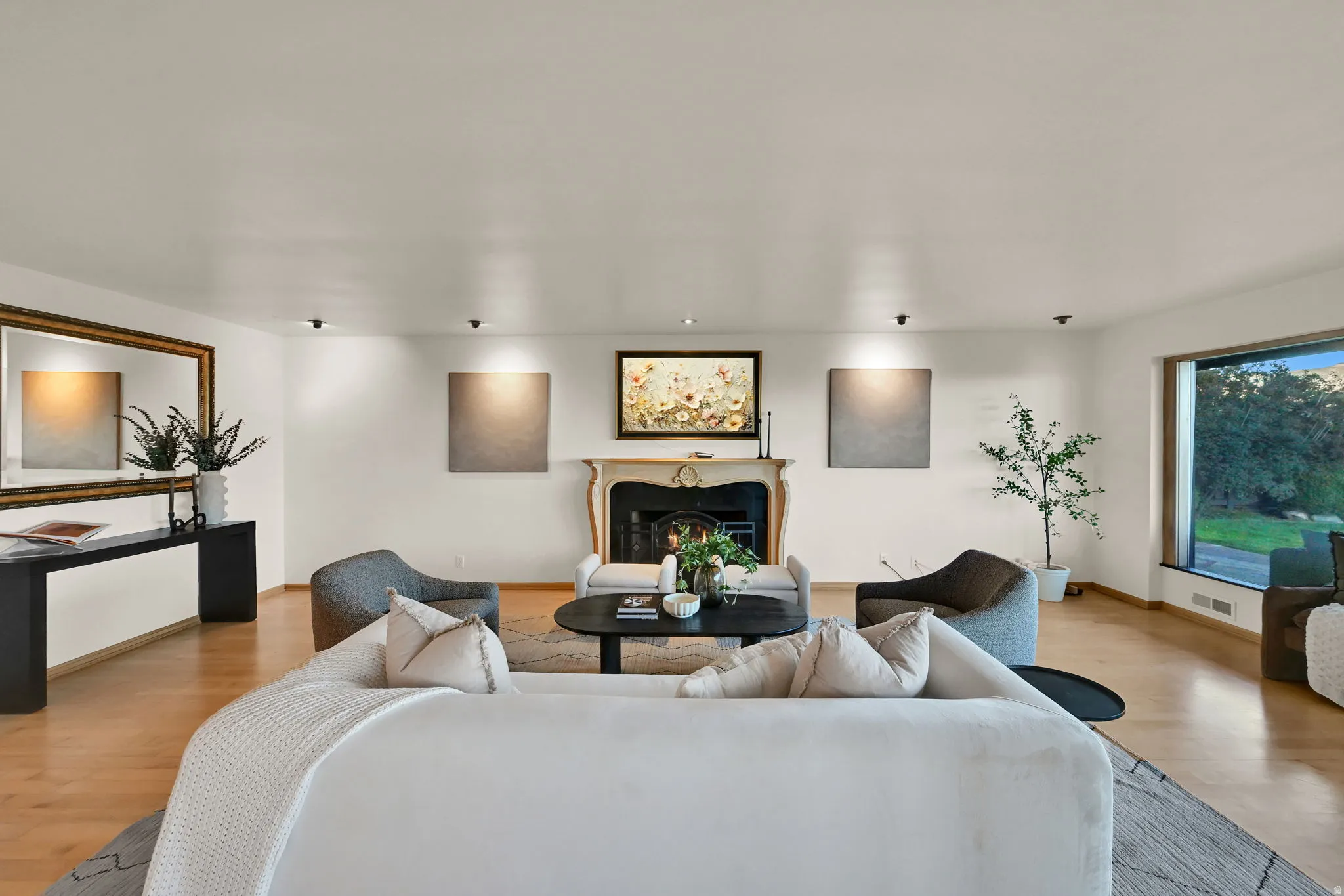 Hardwood flooring, fireplace with ornate mantel, large picture window, and recessed lighting