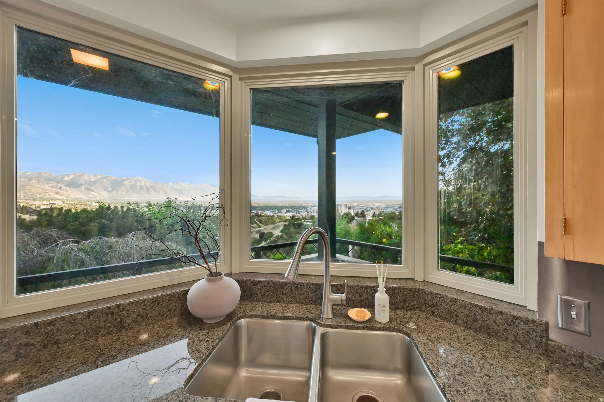 View from kitchen. Dual basin stainless steel sink with a high-arc faucet, set into a speckled countertop