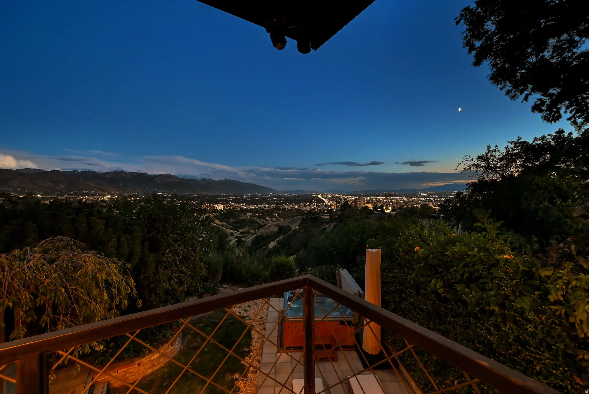 Outdoor patio featuring a hot tub, metal railing, and expansive city and mountain scenery
