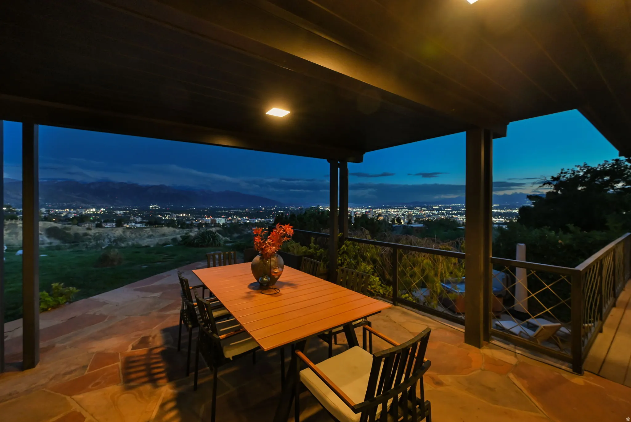 Covered outdoor patio with flagstone flooring, recessed lighting, and a metal railing