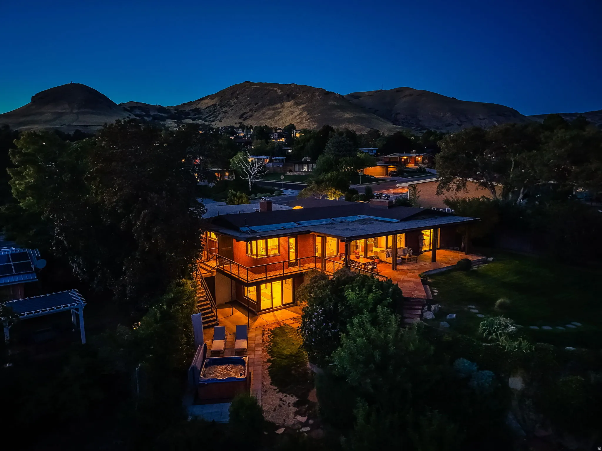 Two-story exterior with expansive windows, multiple balconies, an outdoor patio, and a spa area