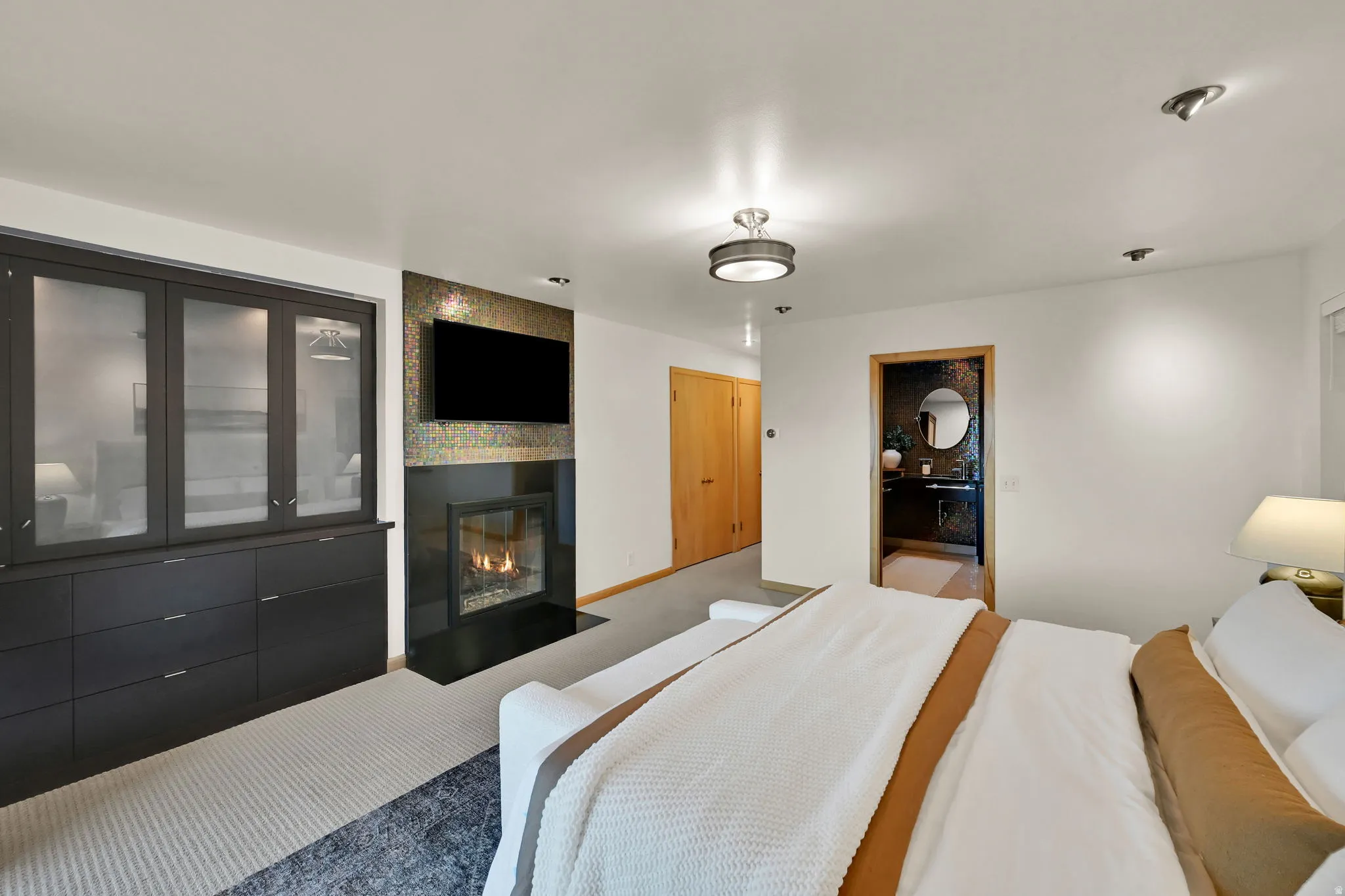 Built-in cabinetry with glass doors, a modern fireplace with a dark surround, mosaic tile accent wall, and a flush-mount ceiling light