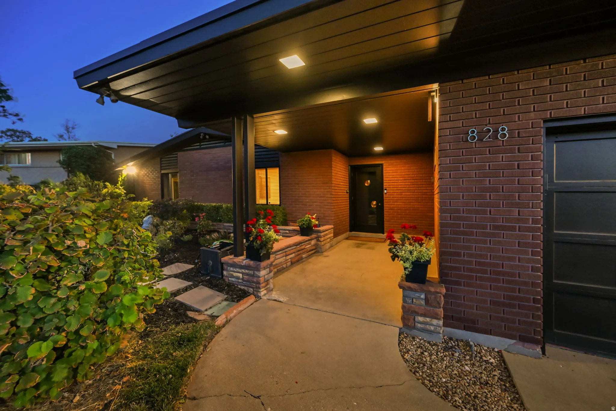 Brick exterior with dark trim accents, covered entry with recessed lighting, and a dark garage door