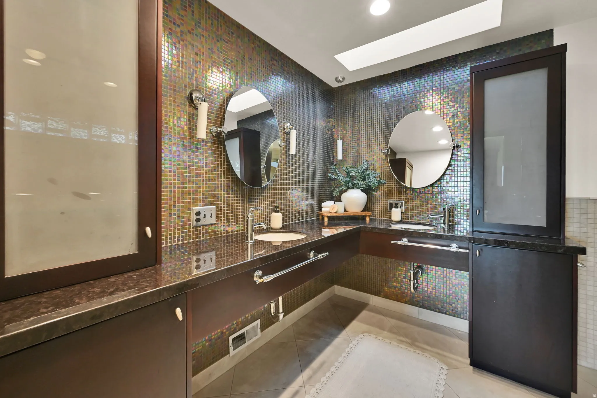Master Bath Dual vanity with integrated sinks, mosaic tile wall, dark wood-finish cabinetry, and overhead lighting