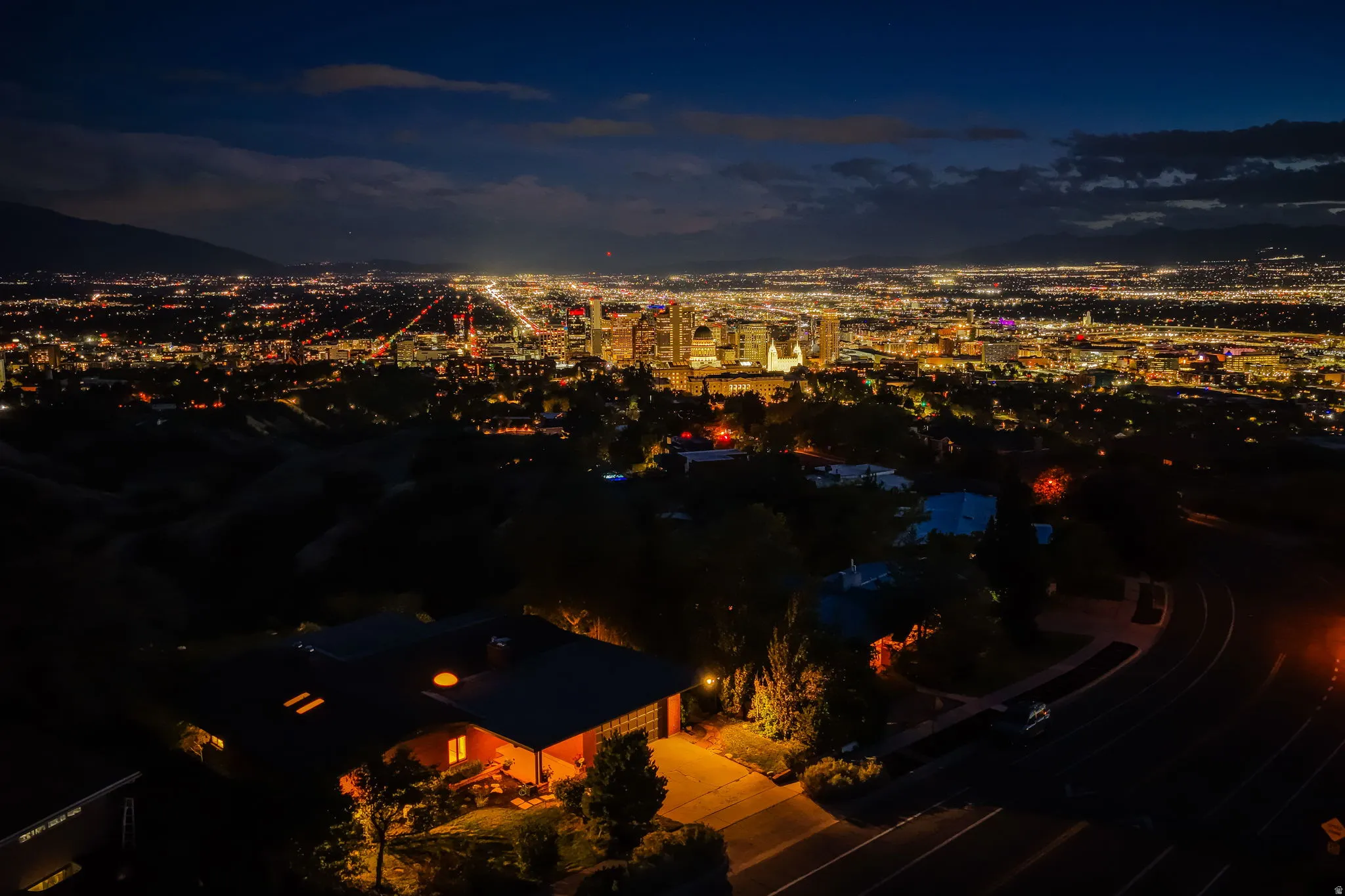 Cityscape backdrop featuring expansive urban lights and distant mountains