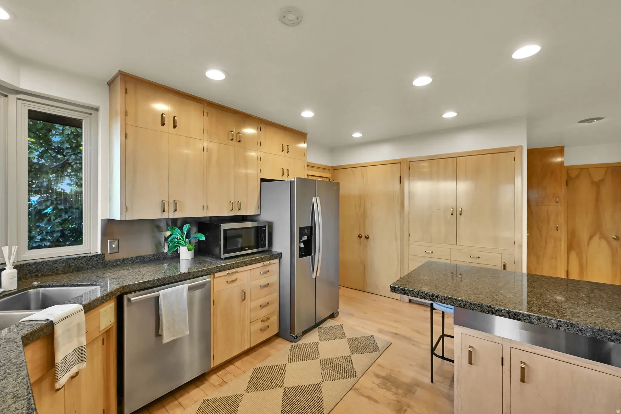 Kitchen featuring wood-finish cabinetry, granite-style countertops, recessed lighting, and stainless steel appliances