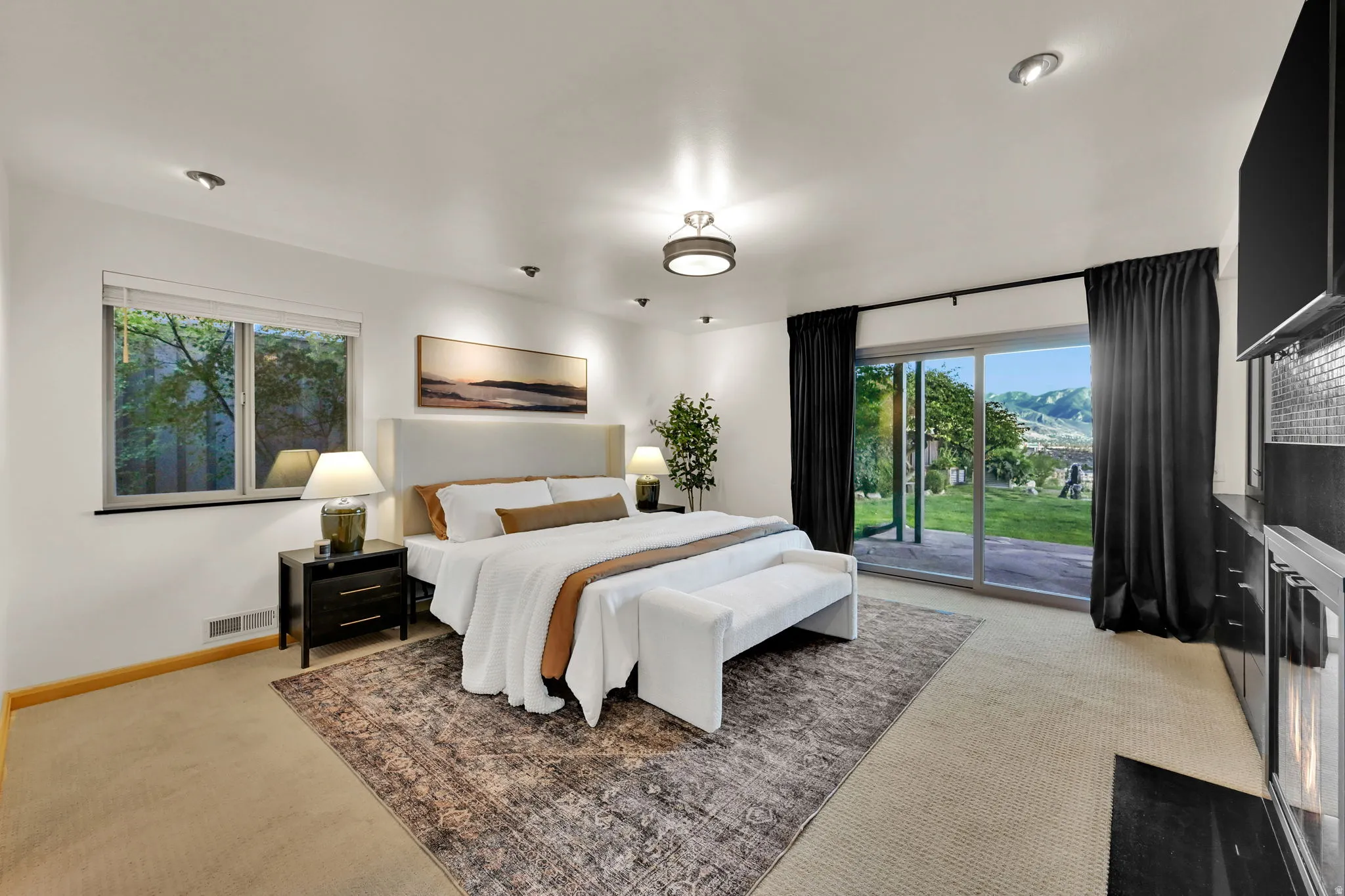 Master bedroom recessed lighting, central ceiling fixture, wall-mounted headboard, sliding glass door, and built-in cabinetry