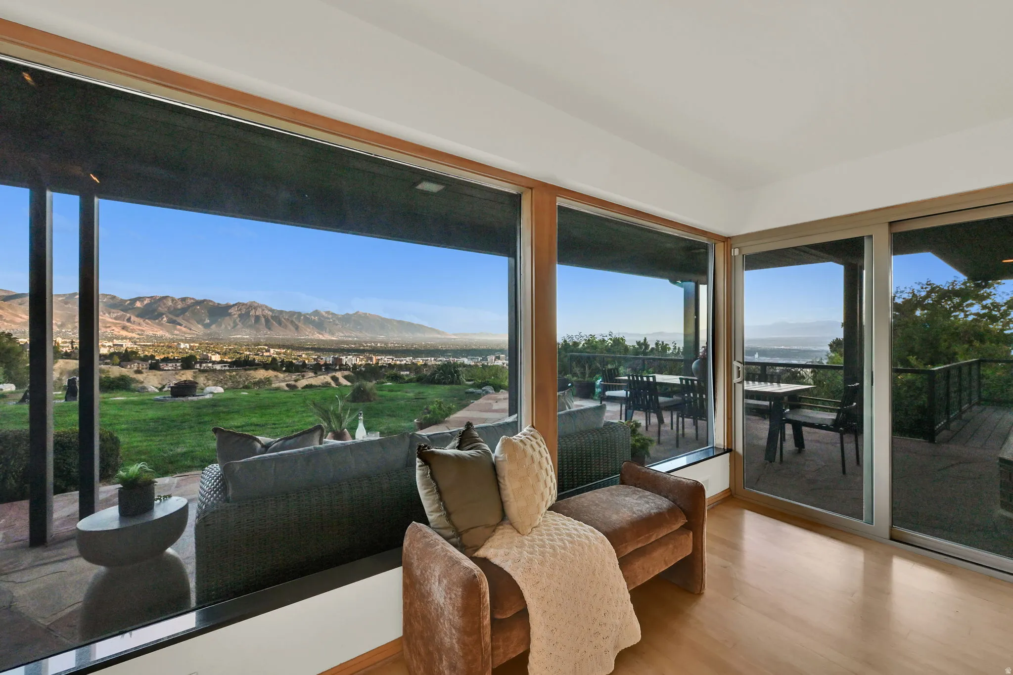 Expansive sliding glass doors, wood-finish flooring, a mountain backdrop, and a private outdoor deck