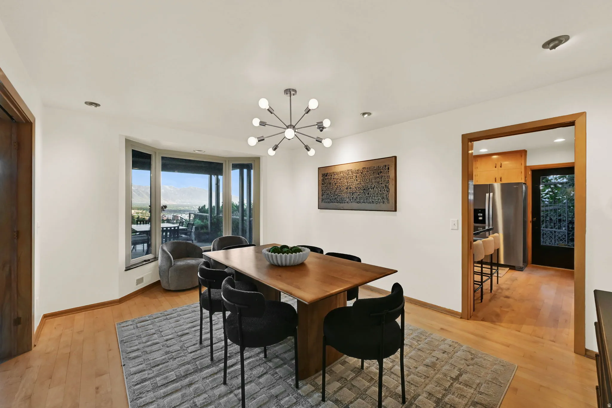 Hardwood flooring throughout, modern sputnik chandelier, bay window, recessed lighting, and a clear story door