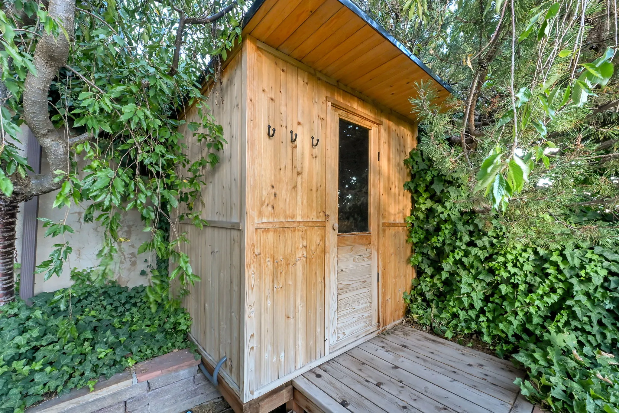 Freestanding wood structure with a peaked roof, wood-plank siding, and a wood-frame door with a window pane