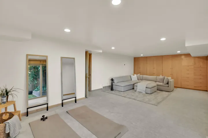 Recessed lighting illuminates the spacious room featuring extensive built-in wood cabinetry and a neutral carpeted floor