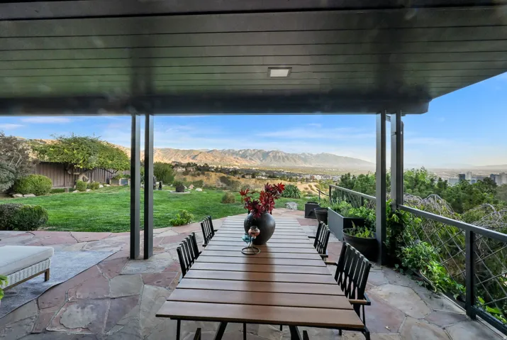 Covered patio with flagstone flooring, black metal railing, and expansive mountain scenery