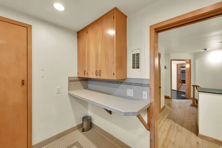 Upper cabinetry with wood-finish doors, a tiled backsplash, and an integrated countertop