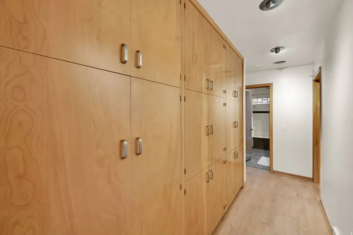 Extensive built-in wood cabinetry with metal hardware, light wood-finish flooring, and recessed ceiling lighting
