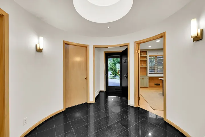 Curved entryway featuring black tile flooring, recessed lighting, and modern wall sconces