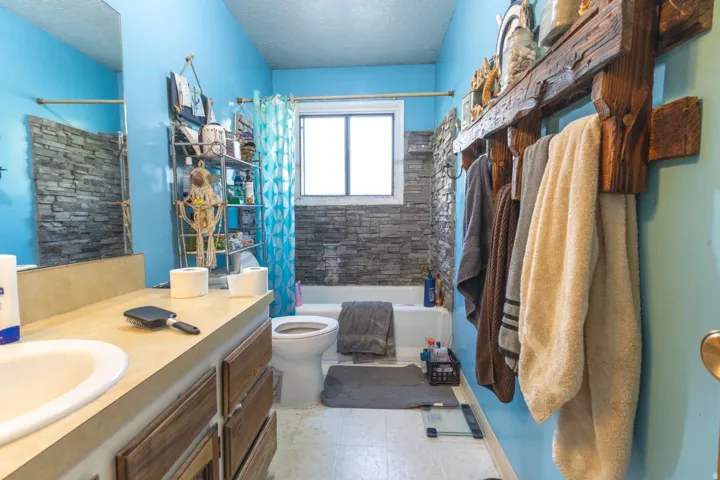 Full bathroom featuring a single vanity, integrated sink, and wood-finish cabinetry