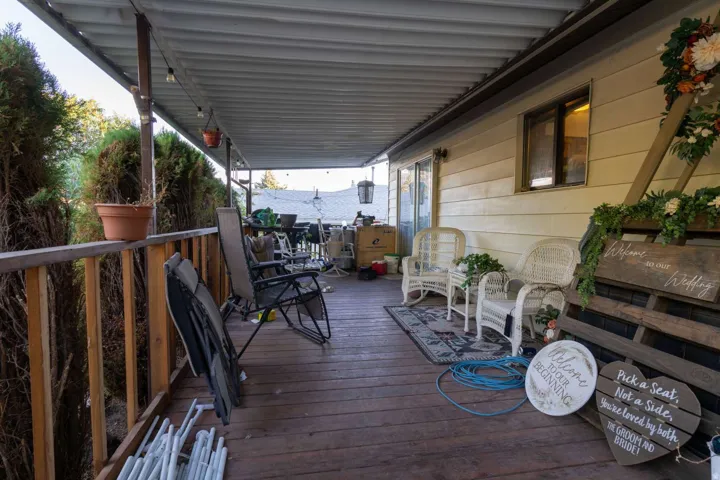 Covered wood-finish deck with a wood railing, attached string lighting, and exterior siding