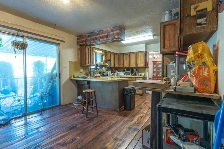 Wood-finish flooring throughout, kitchen with wood cabinetry, and a sliding glass door to an outdoor area