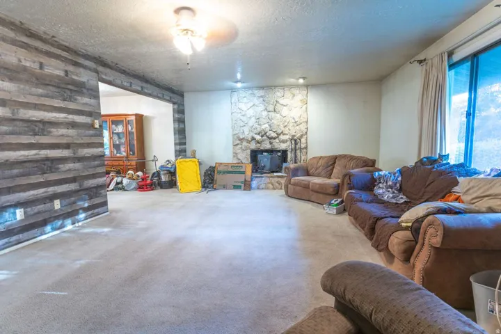 Textured accent wall, stone-finish fireplace, recessed lighting, ceiling fan, large sliding glass door