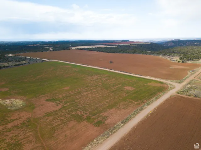 Expansive land with varied terrain including cultivated fields and natural tree lines