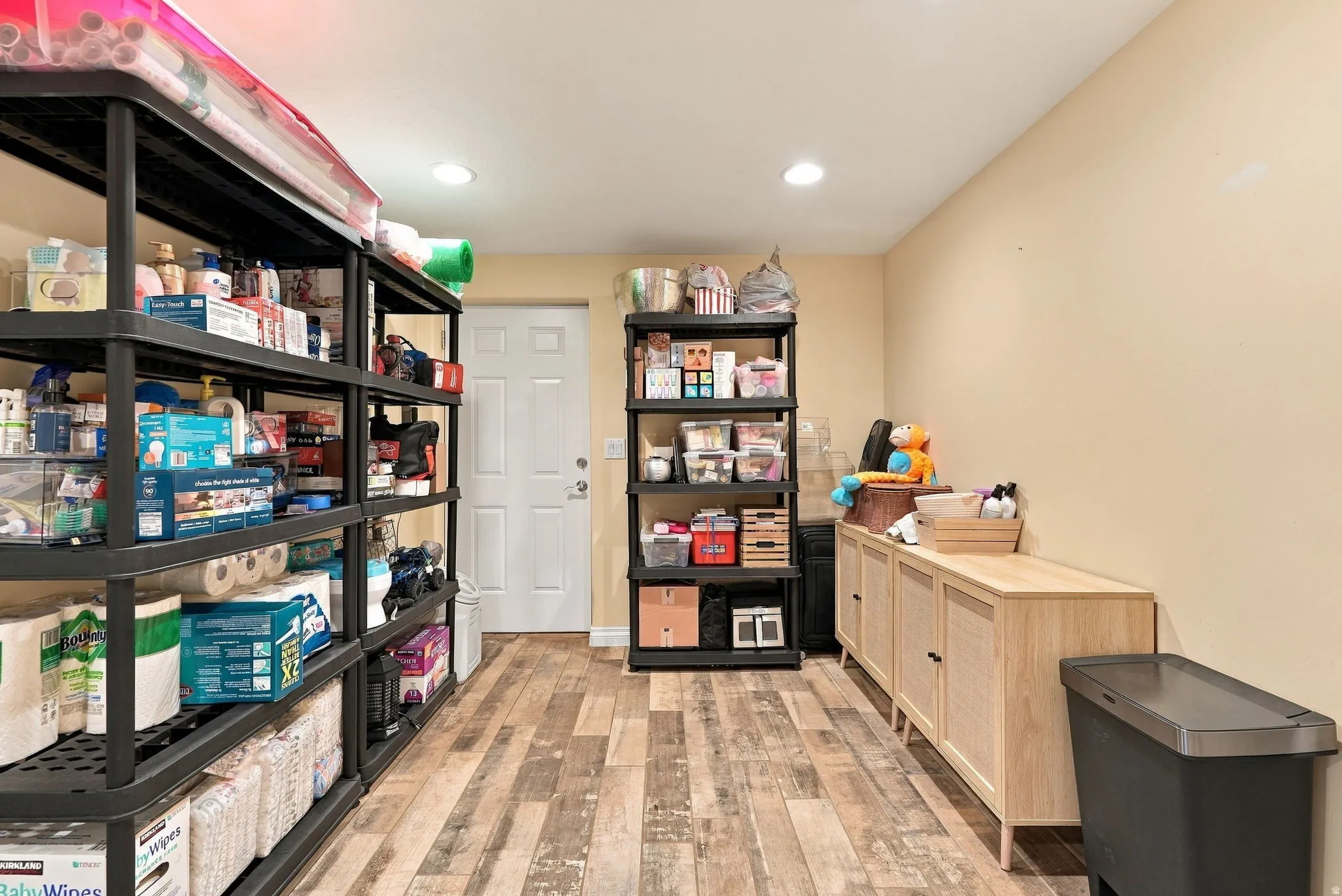 Wood-finish flooring with recessed lighting and a solid white door