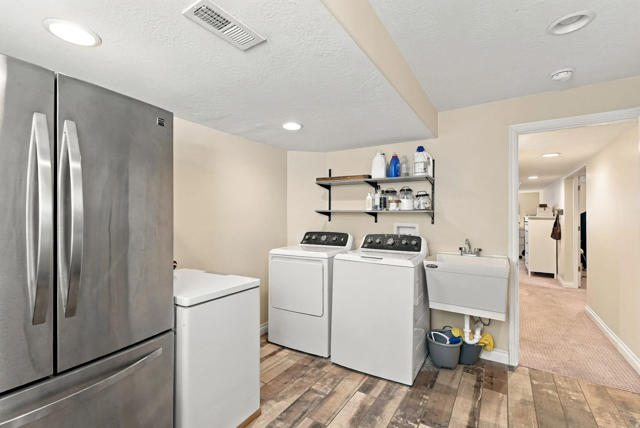 Utility space featuring wood-finish flooring, recessed lighting, and a stainless steel refrigerator