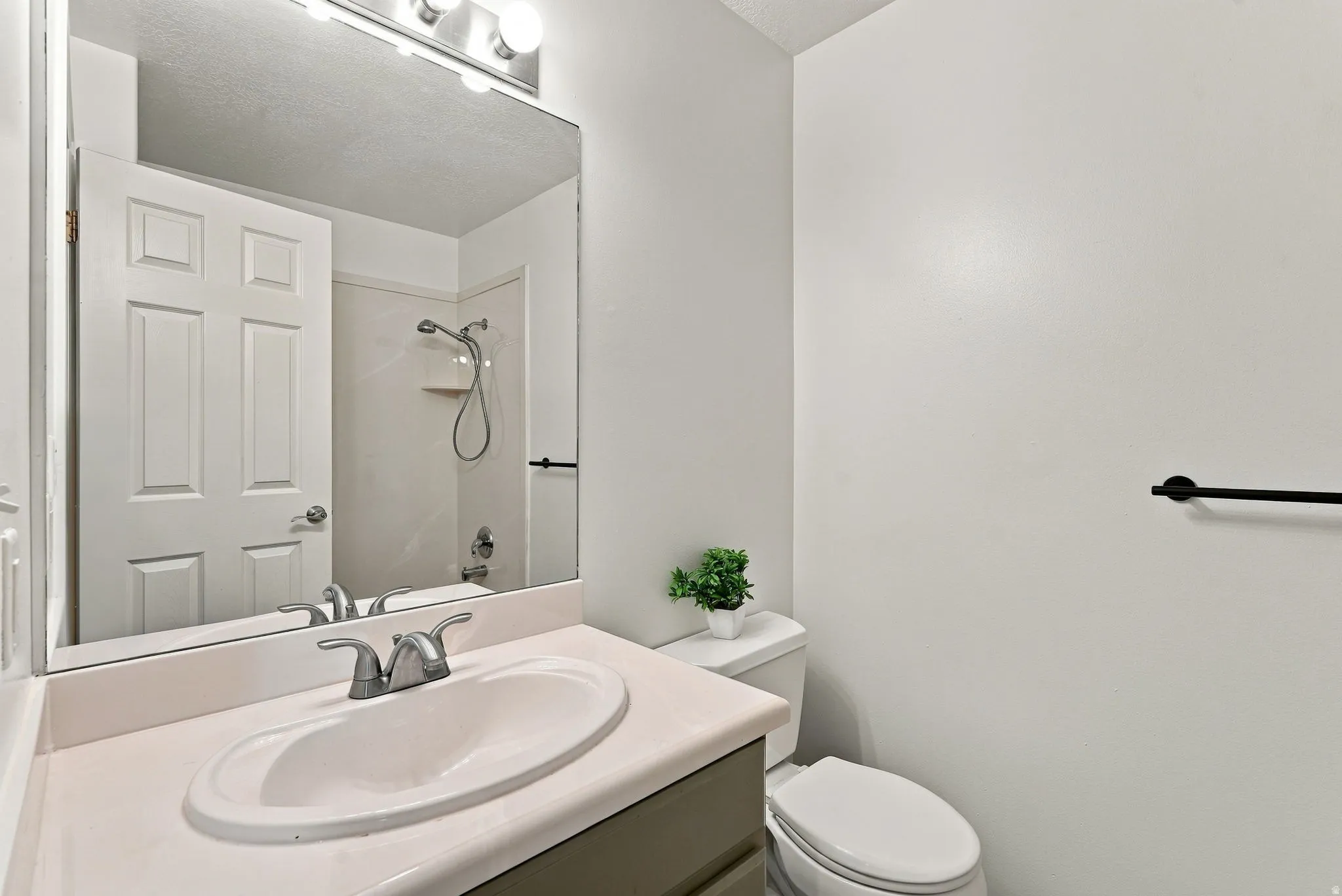 Bathroom featuring a single vanity with an integrated sink, polished chrome faucet, a wall-mounted mirror, and a toilet